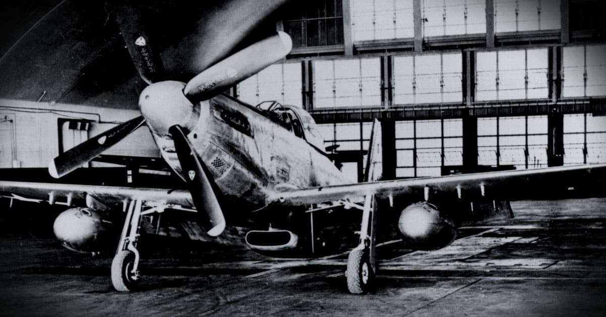 P-51-A P-51D Mustang shown inside a maintenance hangar with extended range drop tanks and hard points
